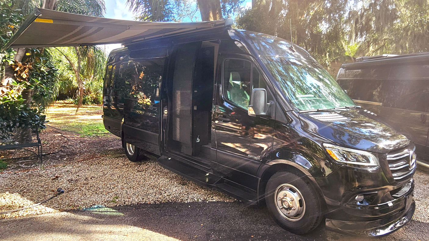 Our black Mercedes-Benz Sprinter camper van, an ideal RV rental, with extended awning and open door, ready for your next adventure.