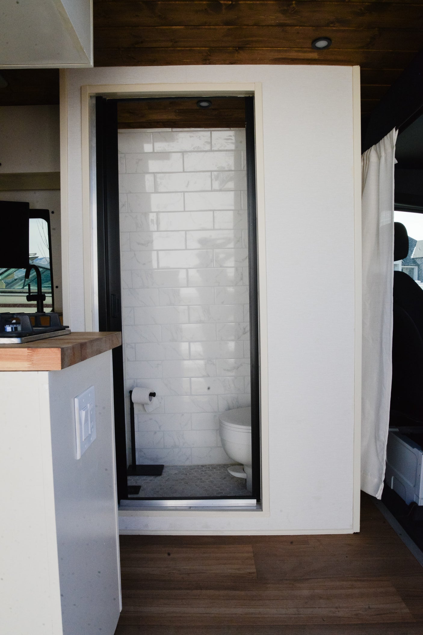 This rv rental showcases a smart interior with a kitchen counter, compact shower/toilet, and stylish subway tiles.