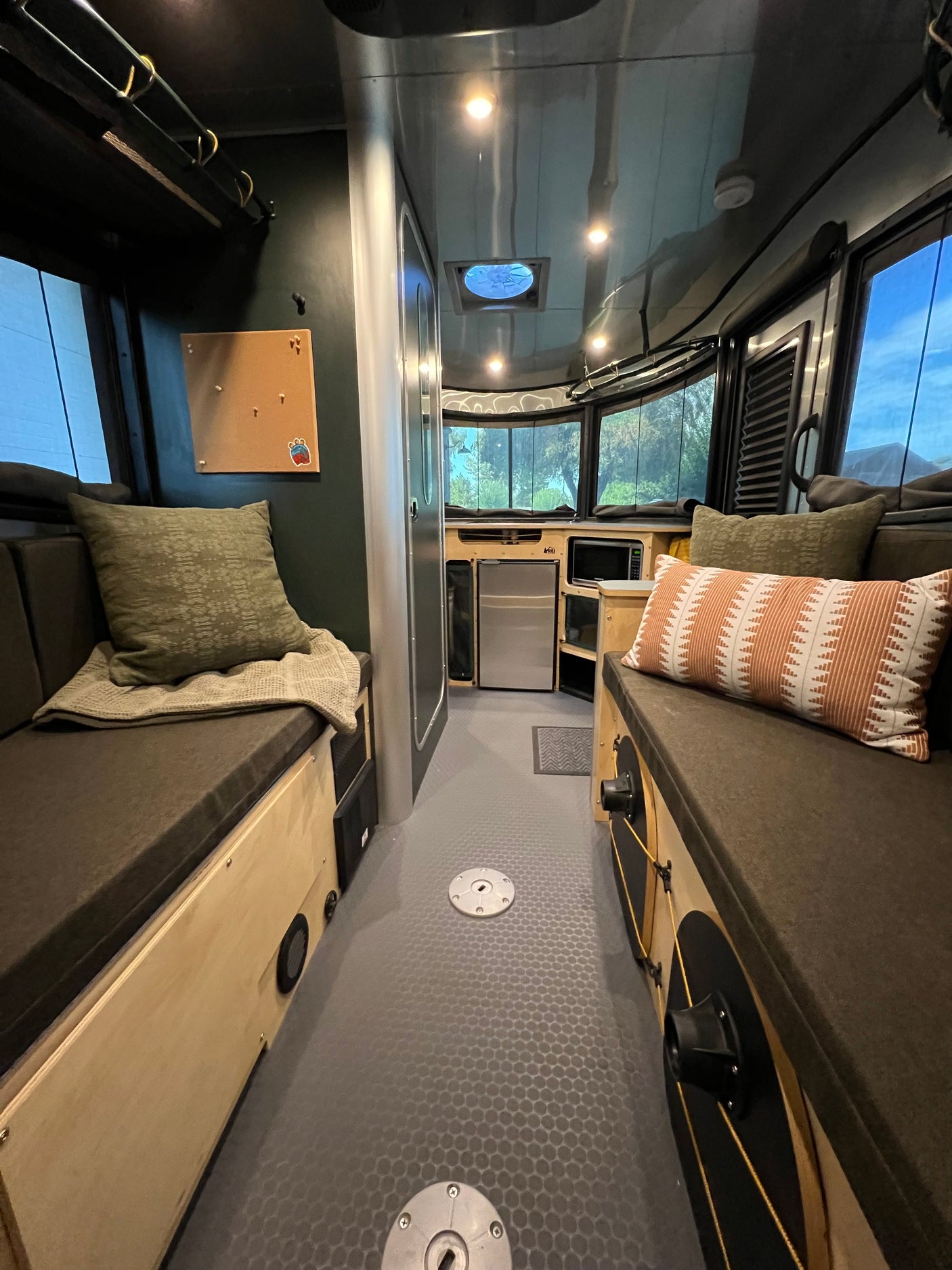 This inviting RV rental interior showcases a cozy sleeping area, compact kitchen, and large windows, perfect for mobile adventures.