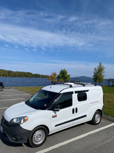 White Ram ProMaster City RV rental van parked by a scenic lake, ready for outdoor adventures.