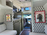 Cozy and personalized RV rental interior with custom sloth and 'DOGUE' art, featuring a compact kitchen.