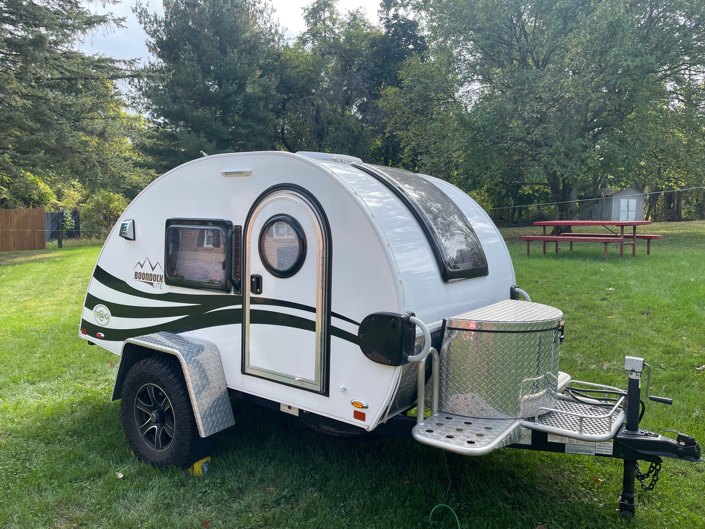 This white Boondock Lite teardrop camper RV rental is parked on grass, ideal for outdoor adventures.