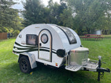 This white Boondock Lite teardrop camper RV rental is parked on grass, ideal for outdoor adventures.