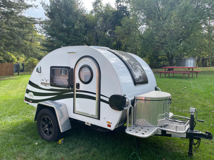 This white Boondock Lite teardrop camper RV rental is parked on grass, ideal for outdoor adventures.