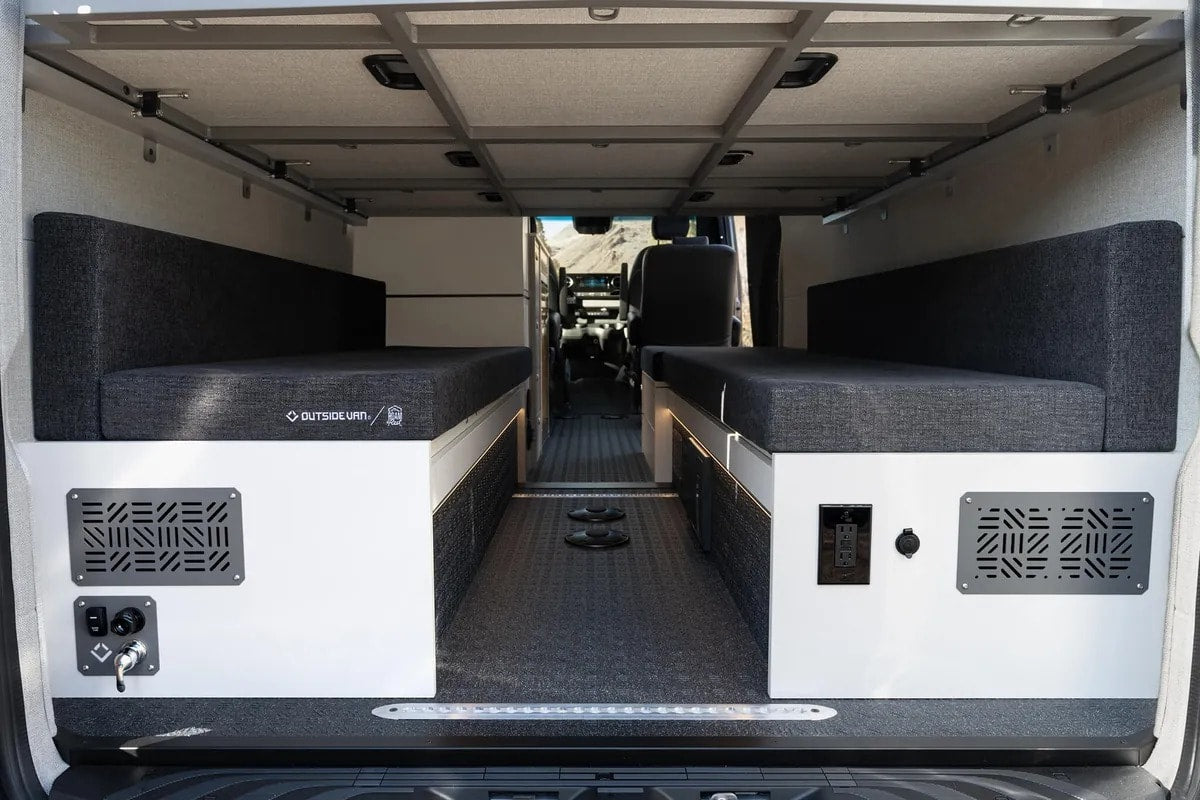  ready for travel.|Inside a premium RV rental: Black leather seats face a versatile bed and storage with visible power outlets.|RV rental interior: luxurious black seats flank a versatile black curtained enclosure — photo 9