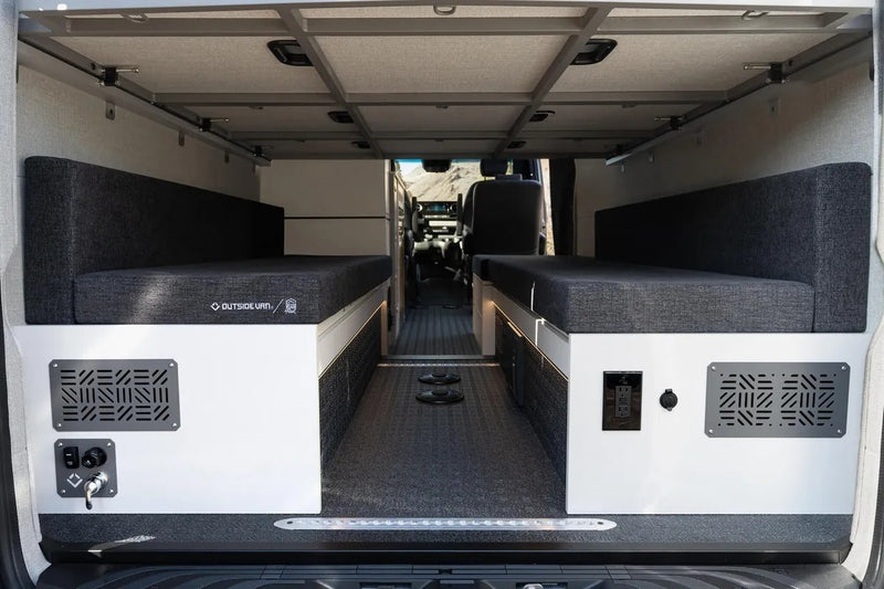  ready for travel.|Inside a premium RV rental: Black leather seats face a versatile bed and storage with visible power outlets.|RV rental interior: luxurious black seats flank a versatile black curtained enclosure — photo 9