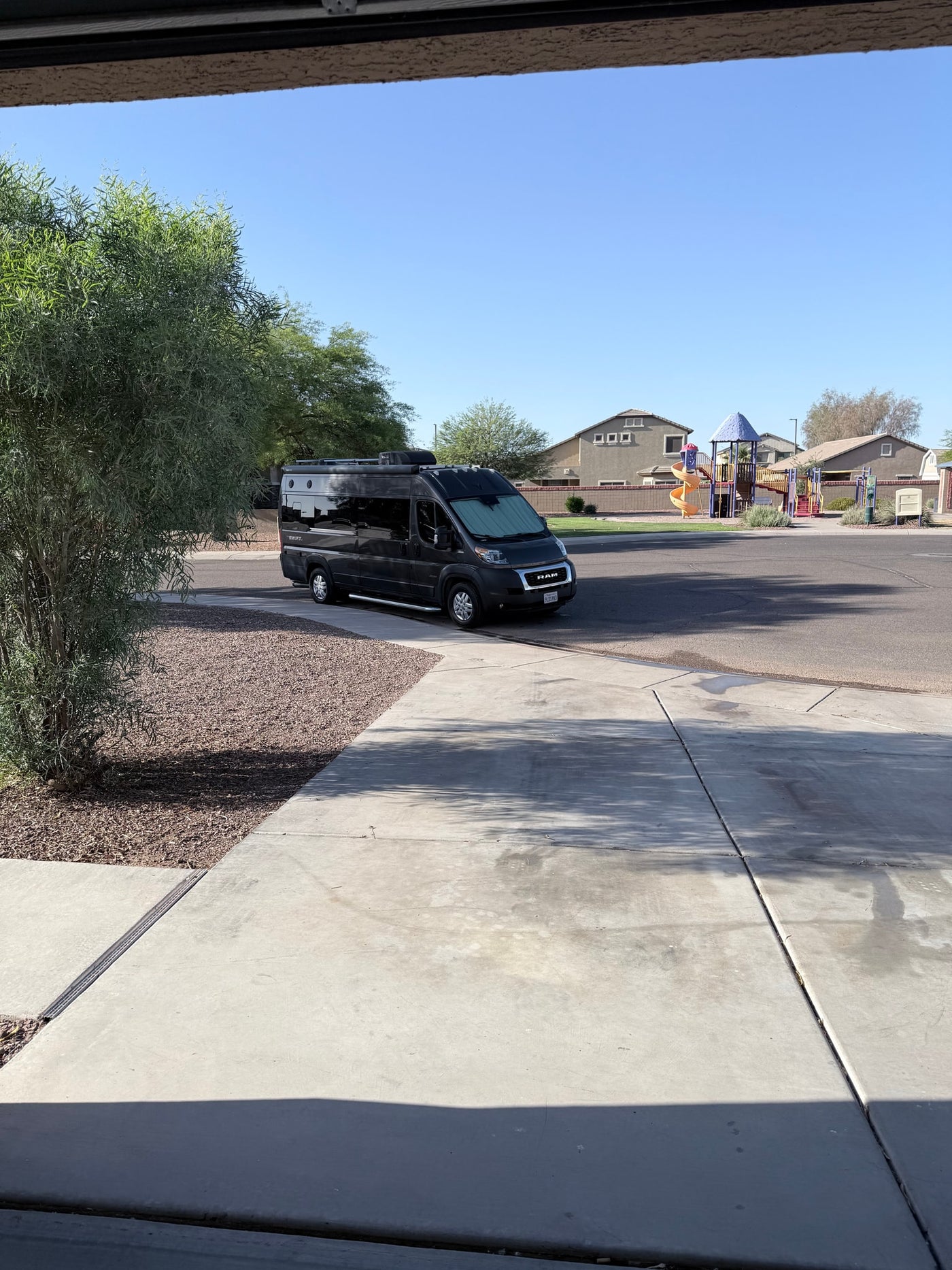Black camper van **rv rental** parked on a residential street, with a colorful playground in the background under a clear blue sky. — photo 7