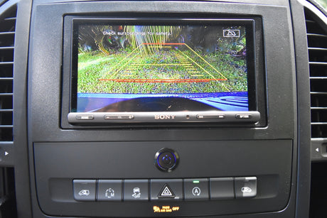 RV rental interior: Dashboard with Sony backup camera showing surroundings and safety lines, plus vehicle controls.