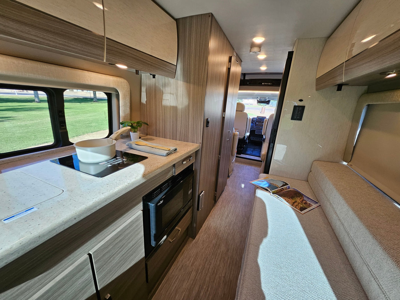  and a relaxing park view. Perfect for road trips.|Cozy RV rental interior featuring a convertible bench bed — photo 6