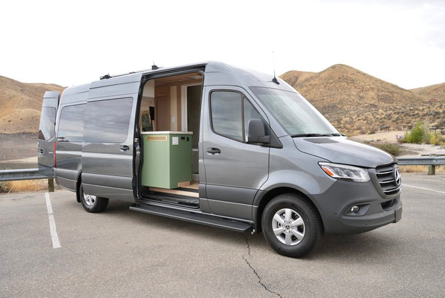  and comfortable seating.|Our RV rental parked among vibrant fall trees at a national park campsite. Coffee & postcards on the bright red picnic table.|Explore in this gray Mercedes-Benz Sprinter rv rental! Its side door is open