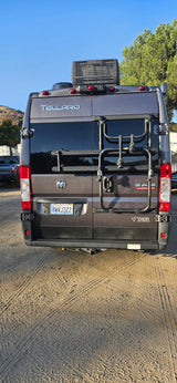 Thor Tellaro RV rental, a gray camper van with a rear bike rack, parked on dirt. Ideal for outdoor adventures.