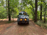 A custom Sprinter camper van, great for an RV rental, parked on a forest path with bright lights.