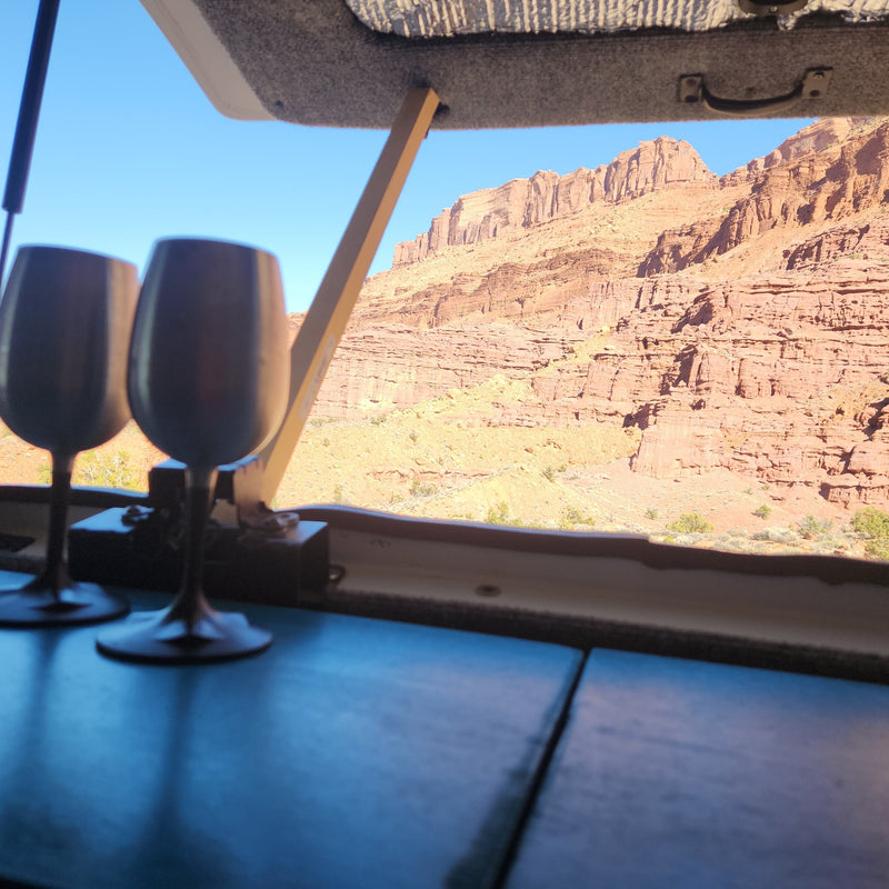From an RV rental, two stemless wine glasses frame a view of a stunning red rock canyon under a clear blue sky. Serene desert landscape. — photo 9