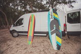 RV rental van on sand, with two colorful Wave Storm surfboards. Ideal for surf adventures!