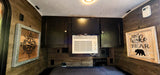 Inside a compact rv rental: wood walls, built-in TV, GE AC unit, and storage cabinets over a bed with rustic decor.