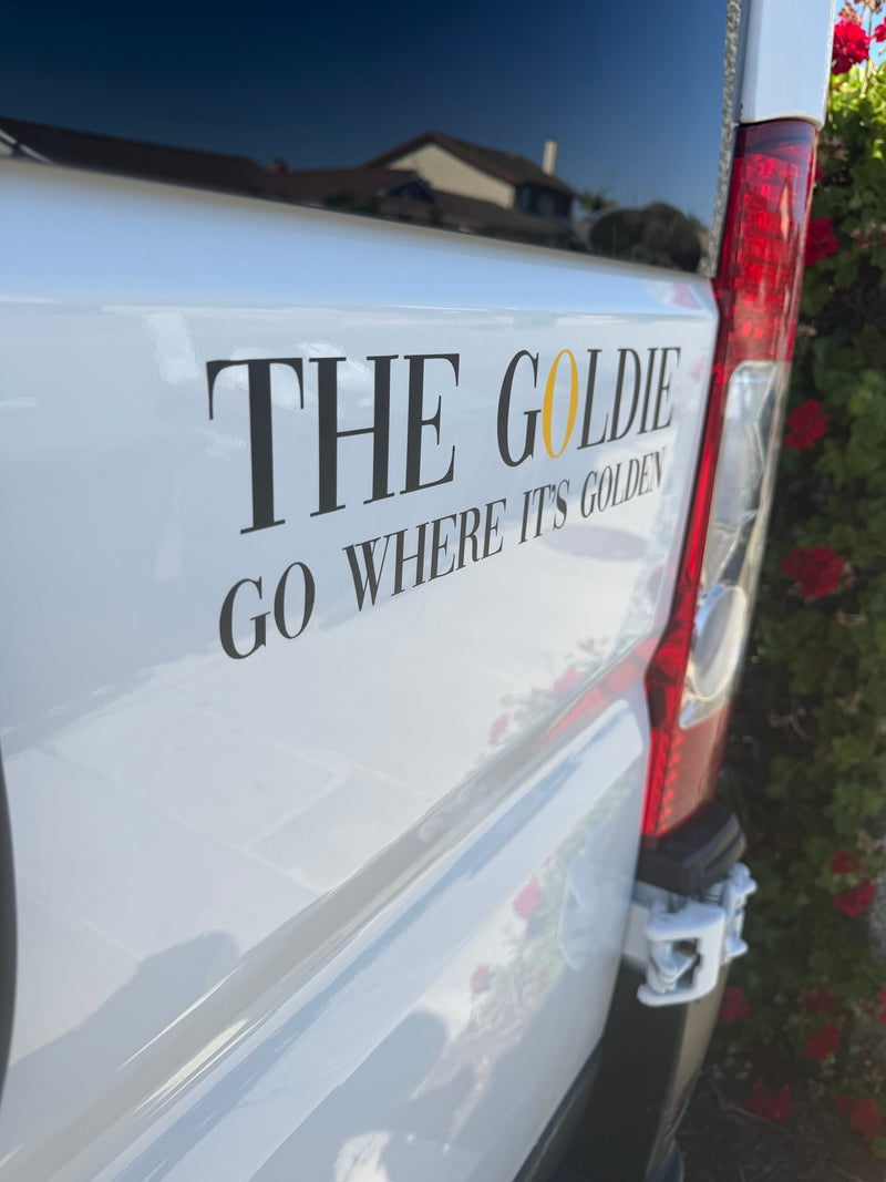  inviting travel and coastal views.|White RV rental van features "THE GOLDIE" branding with "GO WHERE IT'S GOLDEN" slogan. House reflection — photo 3