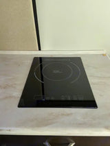 A sleek black induction cooktop on a light marbled countertop, part of an RV rental kitchen setup.