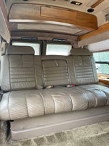 RV rental: Plush leather bench seating inside a comfortable conversion van interior, likely converts to a bed.