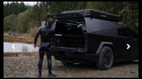 Man showers post-surf by a black Cybertruck with a camper top & surfboards. Perfect rv rental option for outdoor adventure.