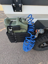Equipped RV rental: portable water and shower system featuring a green jerry can, pump, and blue coiled hose.