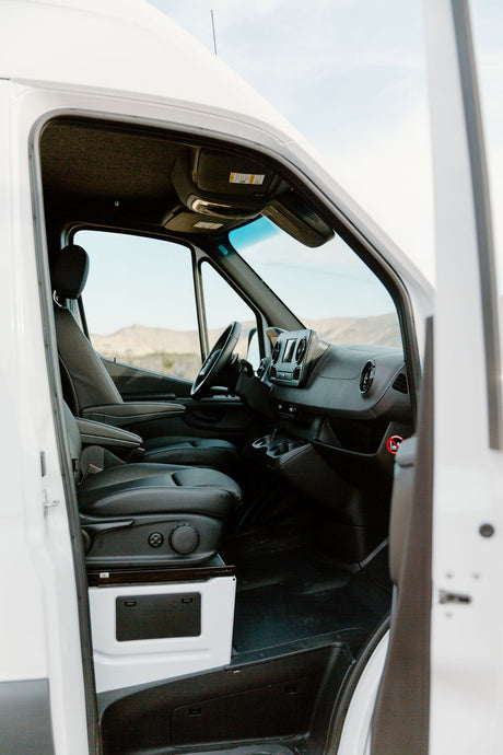 Spacious van interior of an RV rental, featuring driver's cabin, comfortable seats, and modern dashboard. Ready for adventure!