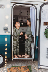 Barefoot kids in striped pajamas giggle inside an RV rental doorway, enjoying cozy camper adventures.