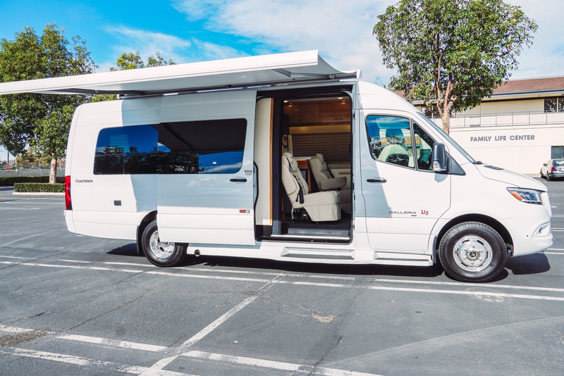 White Coachmen Galleria Li3 camper van parked in a lot, with its side door open to reveal the interior. Awning extended. RV rental. — photo 2