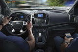 Driving a Ford car, passenger checks phone. A common sight for travel planning or en route to your RV rental pickup.