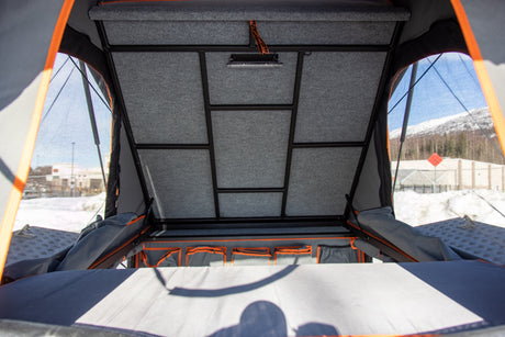 Inside a pop-up rooftop tent, perfect for an RV rental. Features a felt-lined ceiling, integrated light, and organized storage.