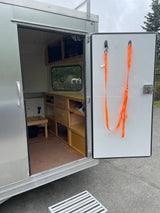 Open door of an RV rental showing custom wood interior, storage, and a view outside. Mobile living.