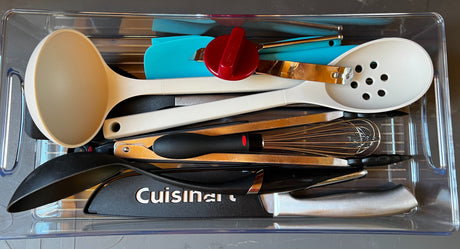 Clear organizer keeps kitchen cooking tools like ladles, spatulas, a whisk, and knives neatly stored, ideal for an RV rental.