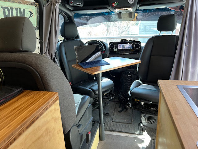 This **rv rental** shows a clever **van conversion** with a laptop desk between the front seats, perfect for **mobile work**.