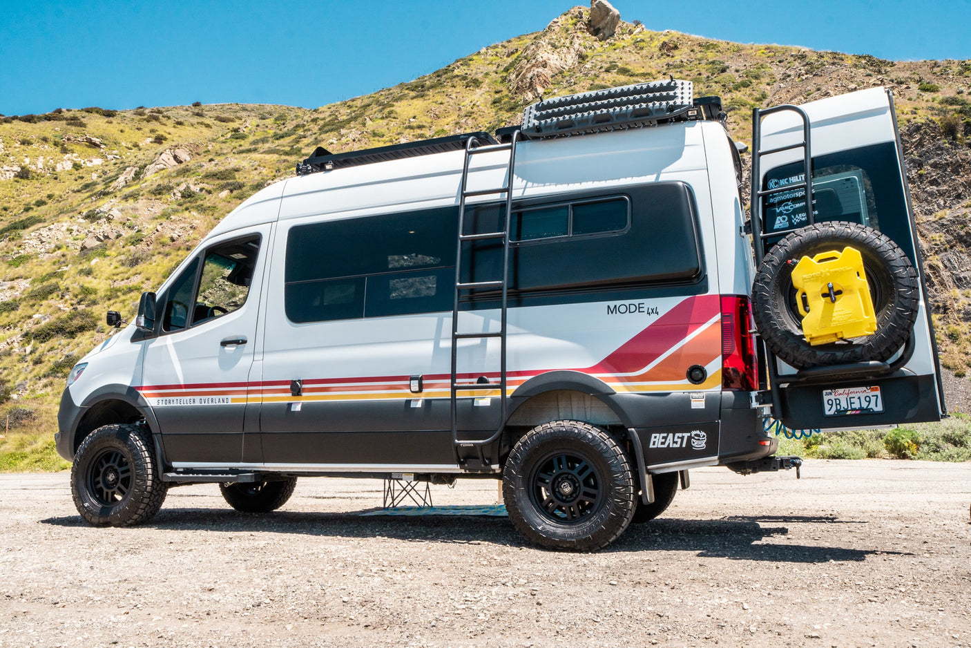 Storyteller Overland Mode 4x4 adventure van, fully equipped for off-road rv rental trips, parked by a sunny hill.