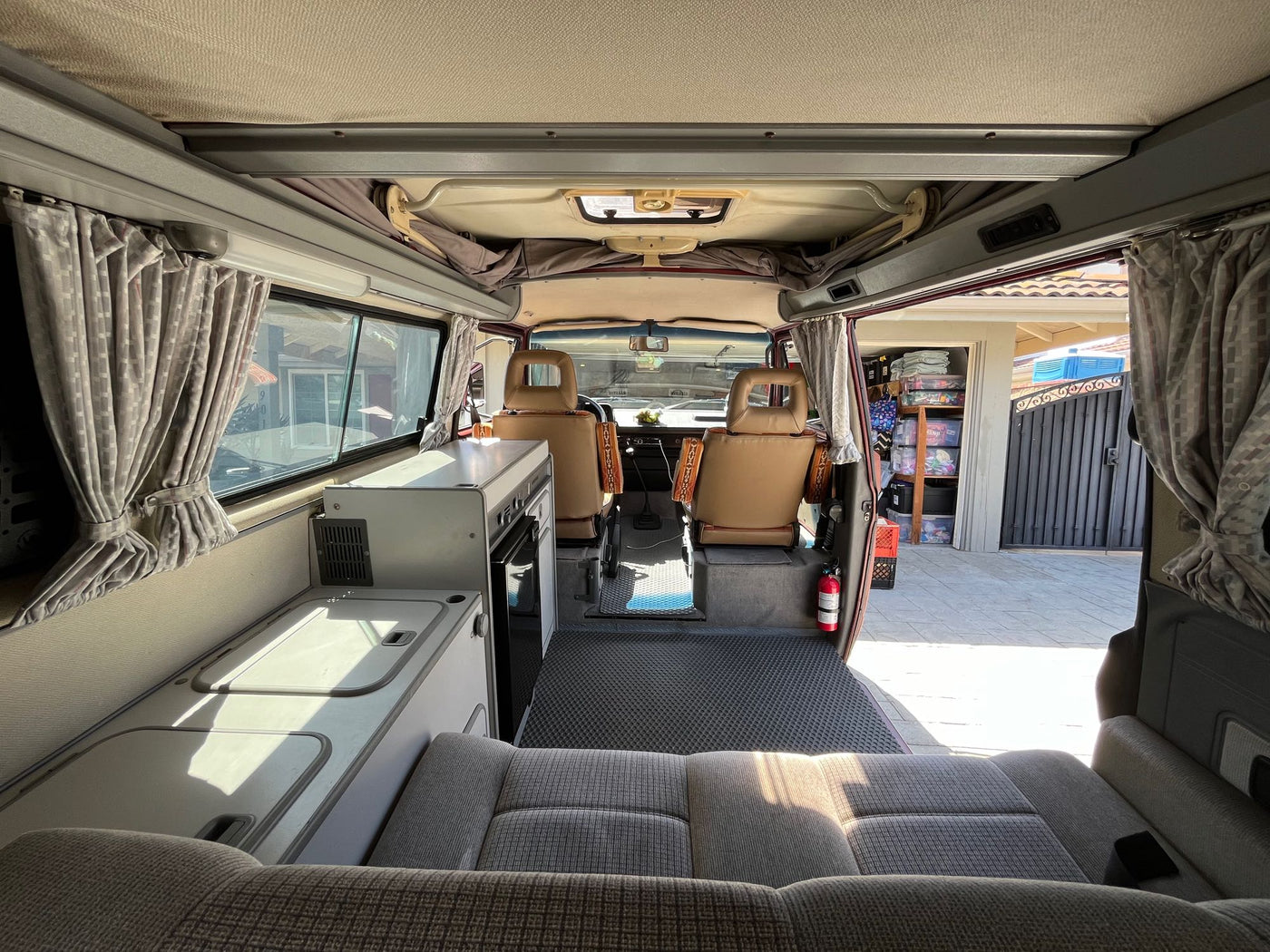  and organized side panel displaying a hanging bag and tied curtains.|RV rental kitchen: Open storage compartments display colorful dishes — photo 11