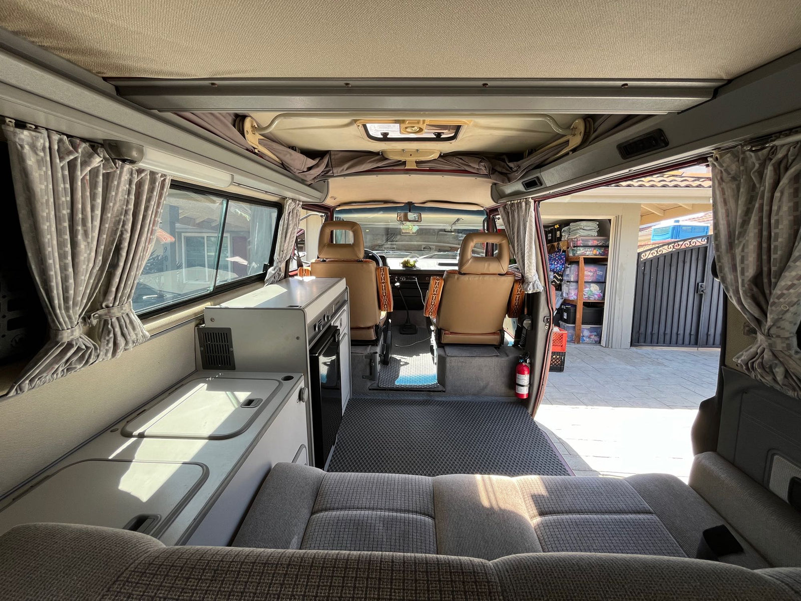 RV rental ready: Explore this camper van's cozy interior, featuring a kitchenette, rear seating, and front cabin.