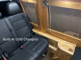 RV rental interior: passenger seat, wooden window trim with integrated USB charger & cupholder for convenience.