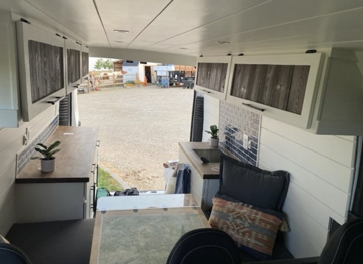  featuring a roof rack and side ladder for adventure.|Spacious rv rental van interior with comfortable gray passenger seating and overhead storage for travel.|RV rental interior: A cozy camper van dining area with a map table and comfy bench seats. Perfect for travel.|Inside a bright RV rental — photo 7