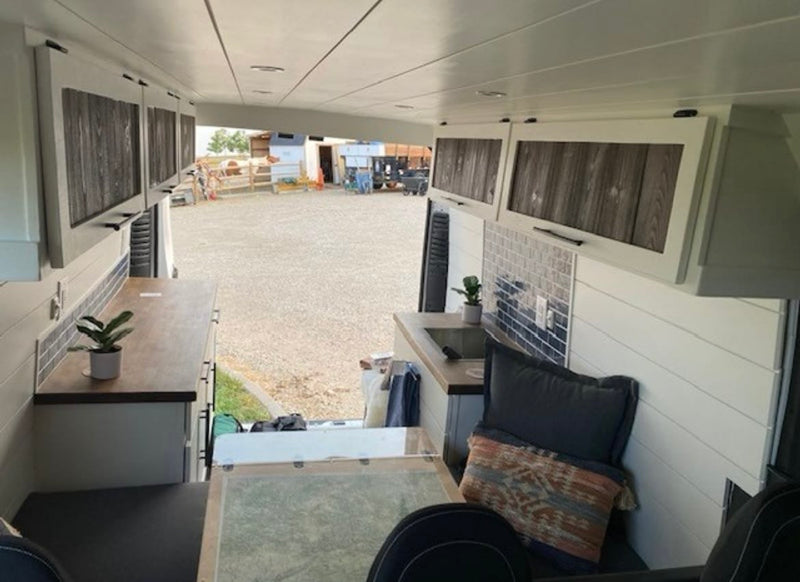  featuring a roof rack and side ladder for adventure.|Spacious rv rental van interior with comfortable gray passenger seating and overhead storage for travel.|RV rental interior: A cozy camper van dining area with a map table and comfy bench seats. Perfect for travel.|Inside a bright RV rental — photo 7
