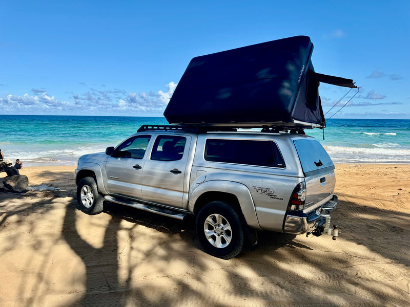 A silver Toyota Tacoma truck with an iKamper rooftop tent on a sandy beach, perfect for your next RV rental adventure. — photo 4