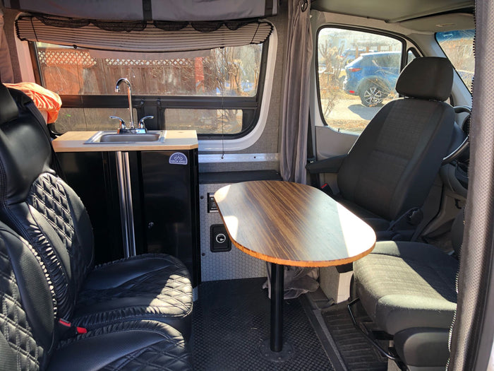 RV rental interior: modern camper van with compact kitchenette, dining table, and comfortable seating, ideal for road trips.