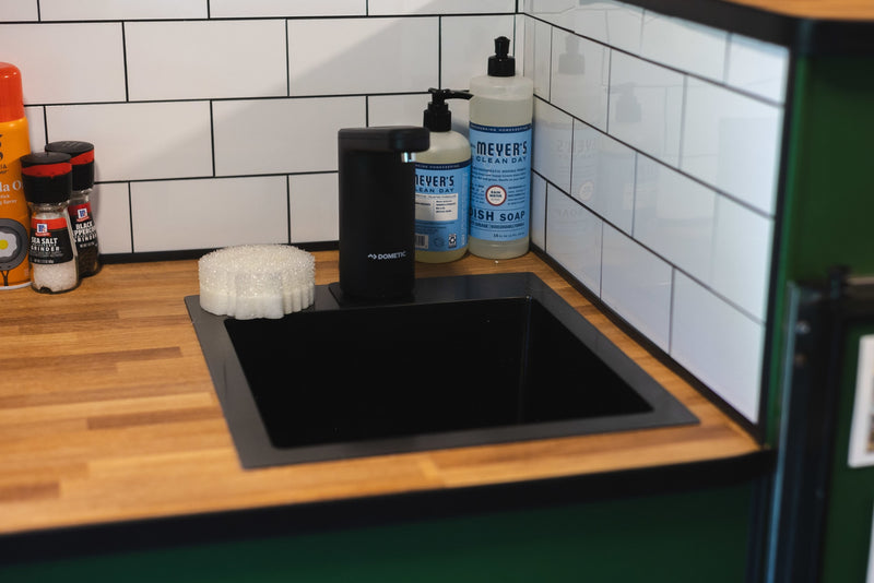 Compact kitchen setup in an RV rental, featuring a black sink, soap dispensers, sponge, and cooking essentials. — photo 6