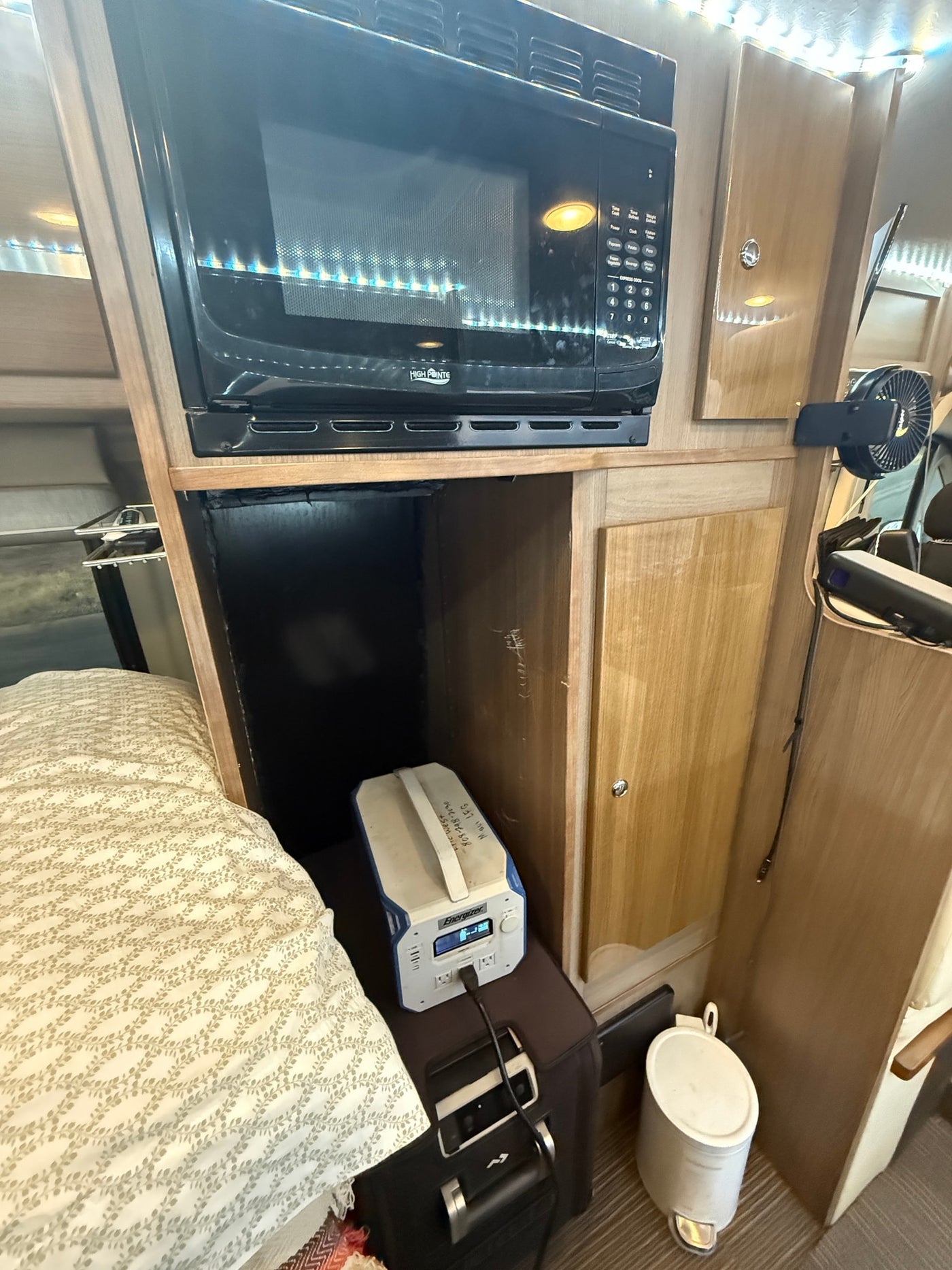 RV rental interior: A compact space with a microwave, cozy bed, and portable power station, highlighting practical amenities. — photo 18