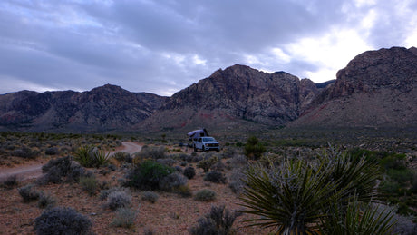 Explore nature with an RV rental: a truck with a rooftop tent ready for mountain camping in the desert.