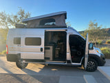 This Winnebago Solis RV rental shows its pop-top extended & side door open, revealing the cozy interior, ready for adventure.