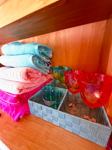 Inside an RV rental: stacks of colorful towels & vibrant glasses in a basket, offering thoughtful amenities.