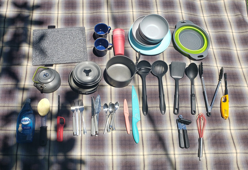 RV rental kitchen setup on a plaid blanket: a complete kit with cookware, dishware, utensils, and cleaning supplies. — photo 8