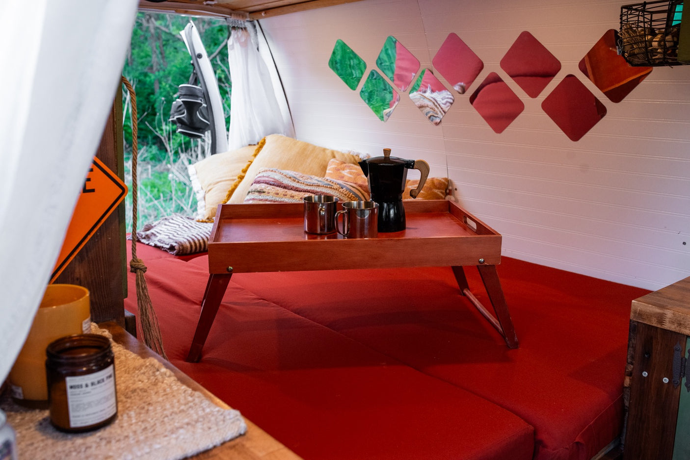 Comfortable RV rental interior showing a red bed, coffee tray, and decorative wall panels for a cozy stay.
