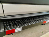 Close-up of a black, textured RV rental step with shiny raised points and red/white reflective strips for safe entry.