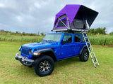 This blue Jeep Wrangler with a purple rooftop tent is available for RV rental, perfect for overlanding & camping.