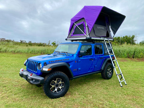 This blue Jeep Wrangler with a purple rooftop tent is available for RV rental, perfect for overlanding & camping.